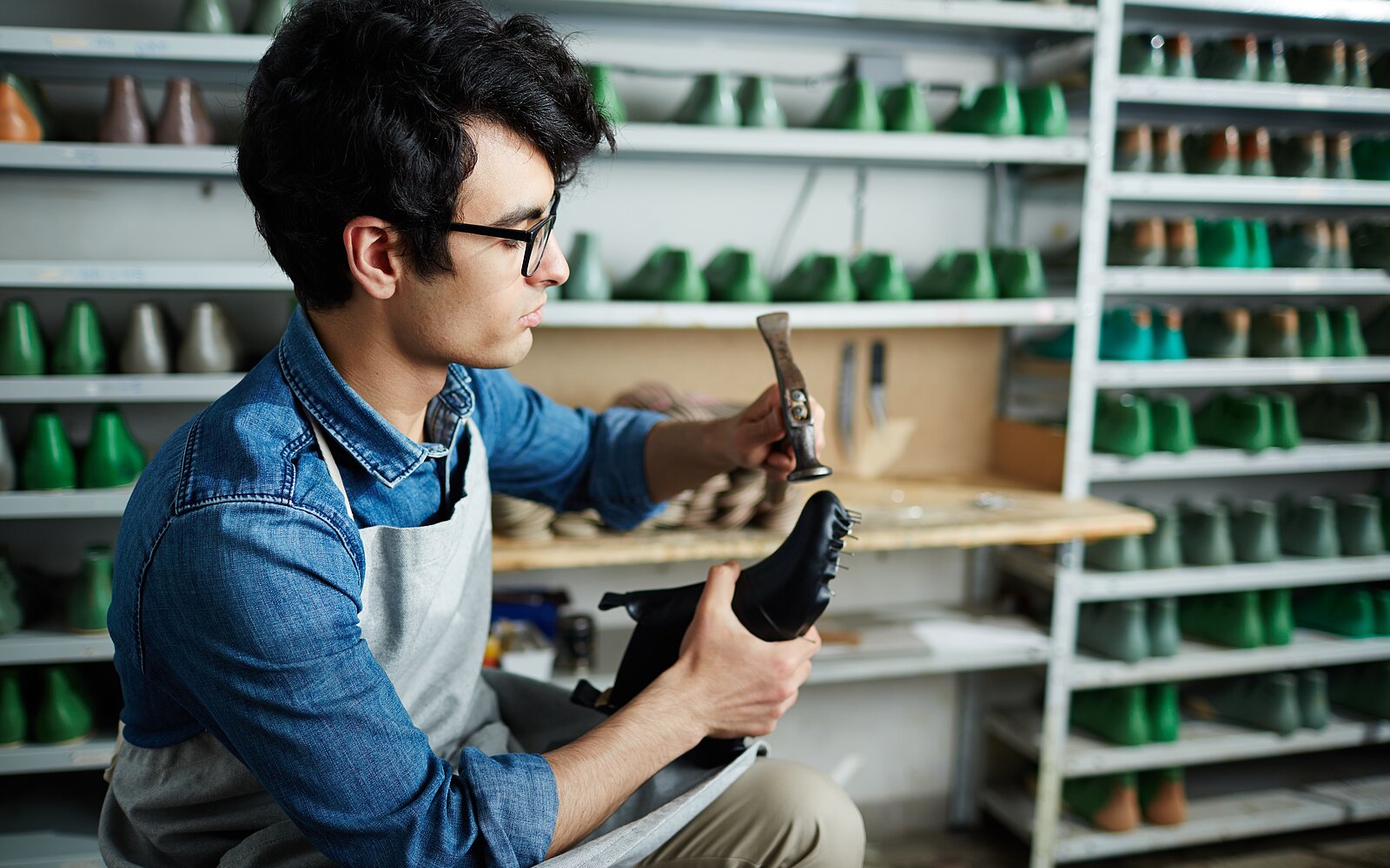 ein Schuhmacher mit einem Hammer in der Hand, der ein paar Schuhe repariert